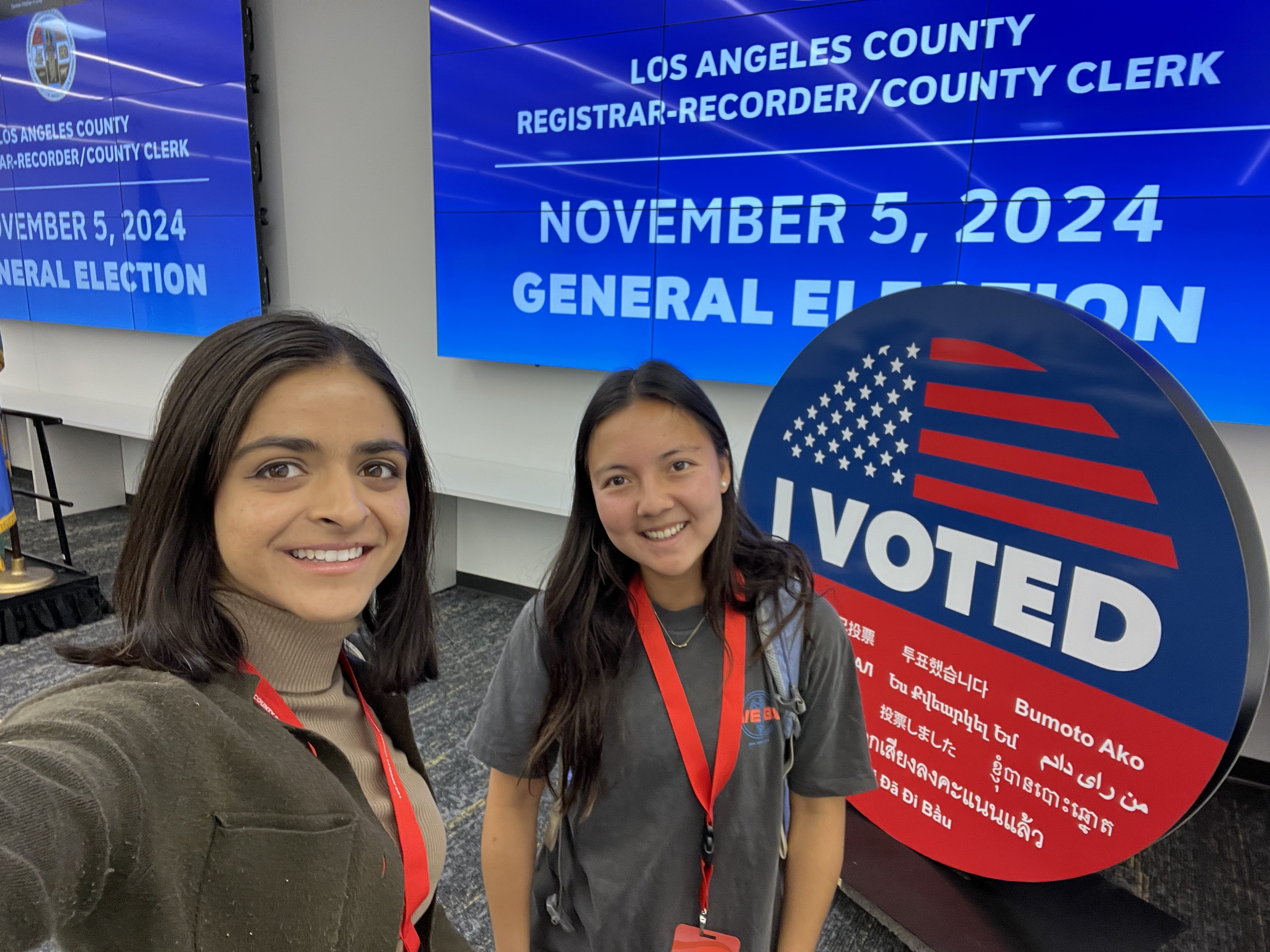 two people in front of "I voted" sign